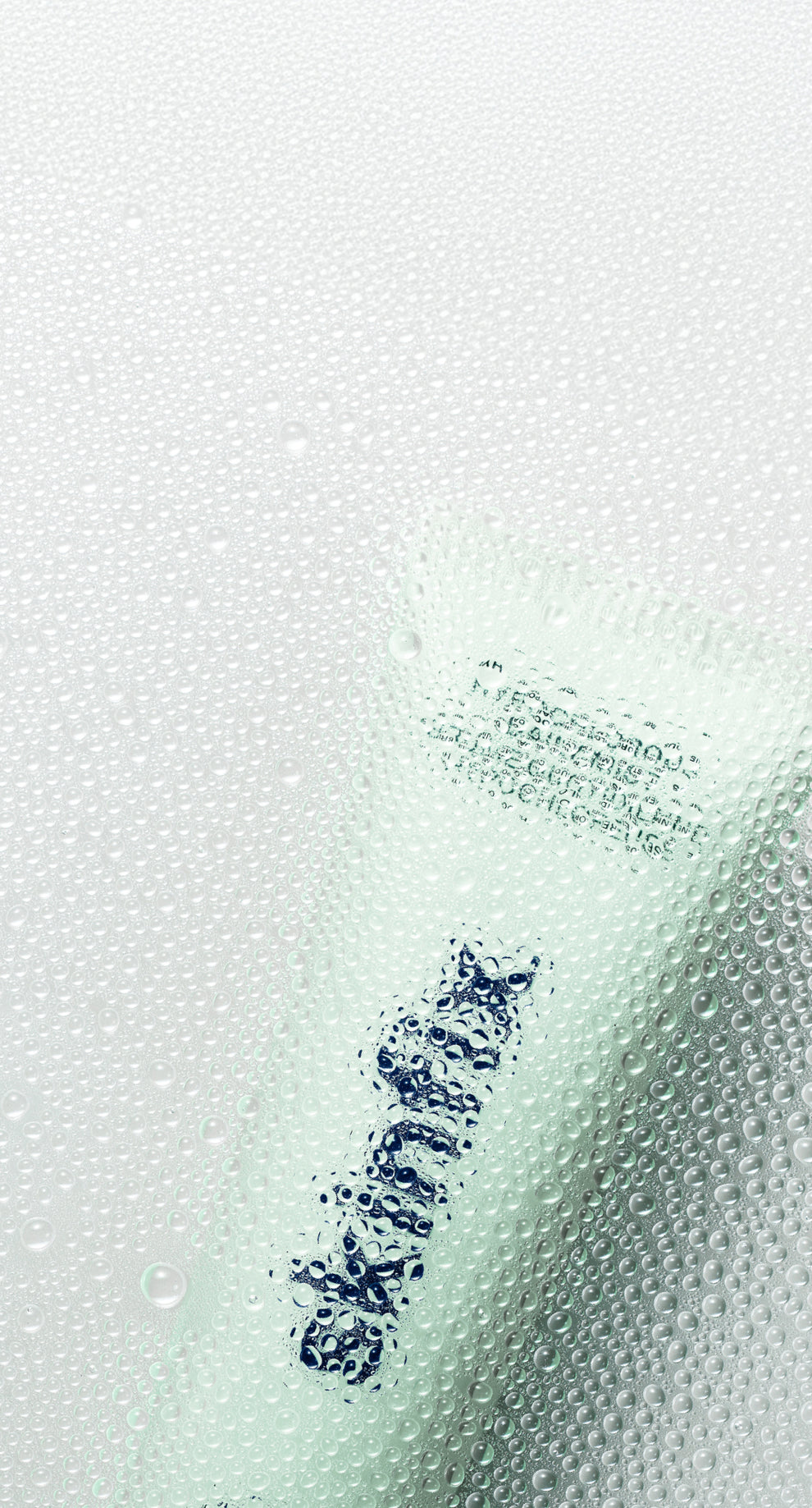 A close-up of a cosmetic tube with water droplets on its surface, showing dark blue text that reads 'SKINFIX'.