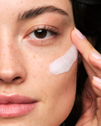 A person applying Skinfix Ceramide Prime Whipped Cream to their cheek