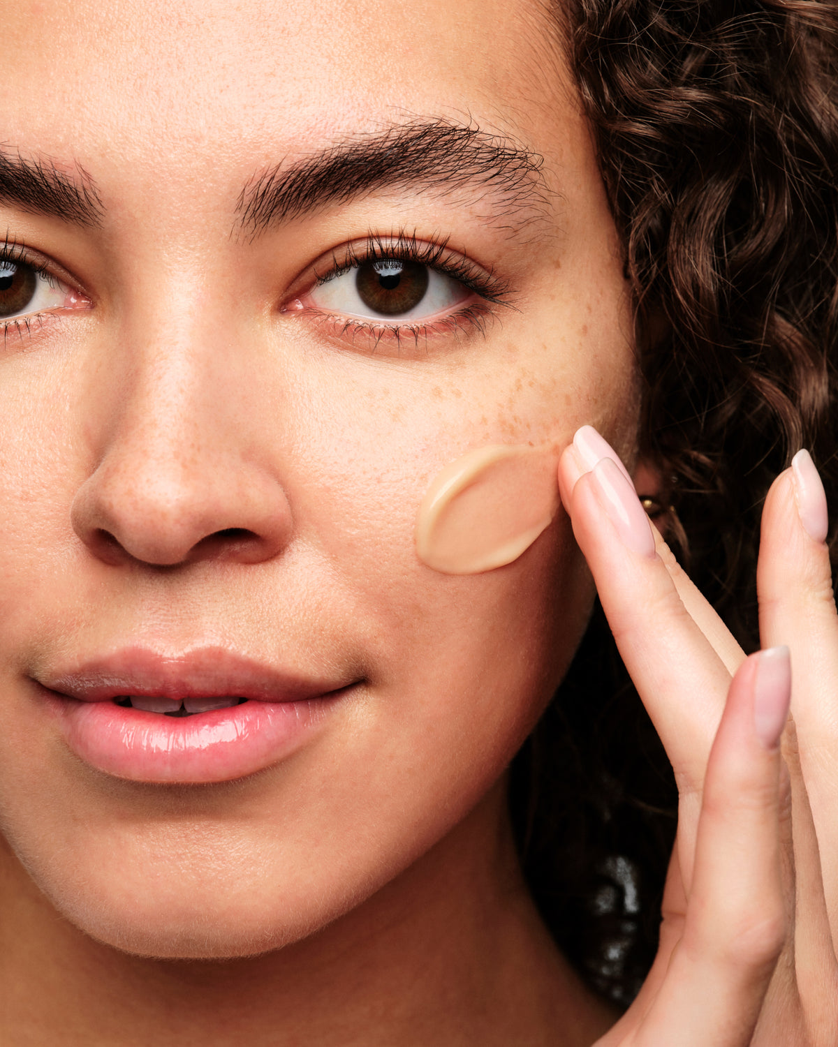 Woman applying Skinfix Exo + Ectoin Intensive Repair Baume to cheek with fingertips.