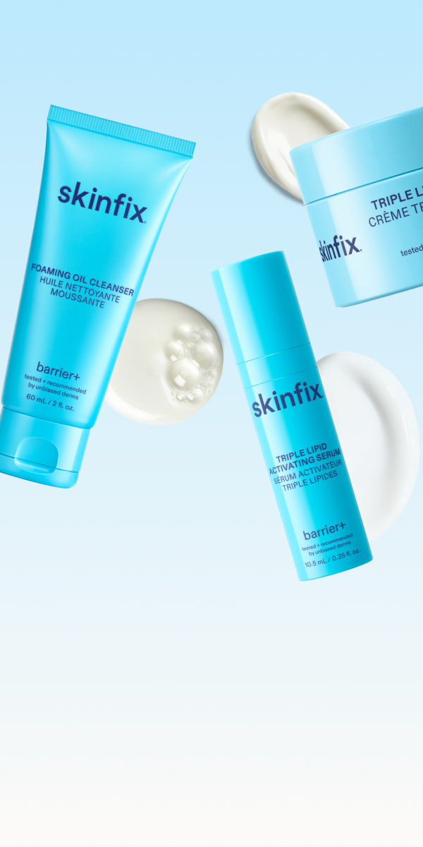 Three blue skincare products from skinfix are arranged on a light blue background with white cream swirls. The products include a foaming oil cleanser, a triple skin barrier cream, and a triple skin barrier moisturizer.