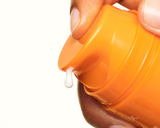 Orange container of Skinfix Vitamin C with a small amount of cream being squeezed out, on a white background.