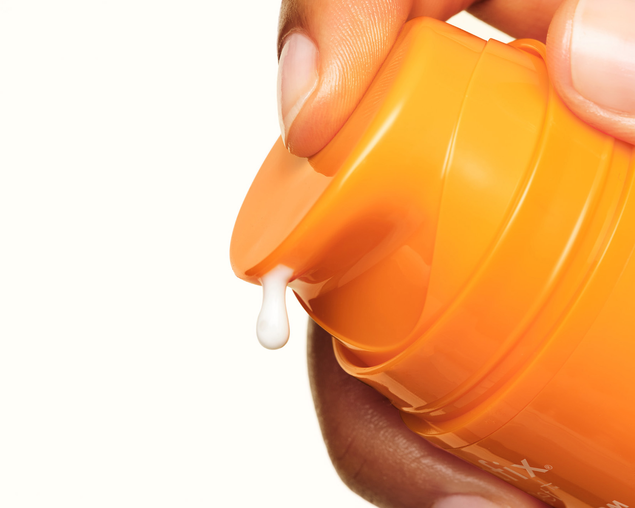 Orange container of Skinfix Vitamin C with a small amount of cream being squeezed out, on a white background.